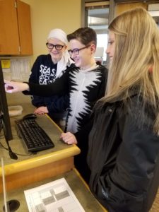 A reference librarian demonstrates a database for two students.