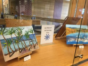 Two oil paintings of landscapes in a display case.