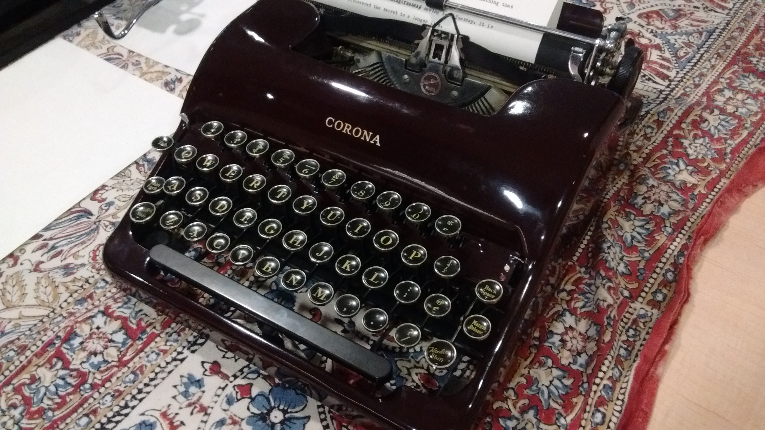closeup of a black, vintage Corona typewriter on a red tablecloth