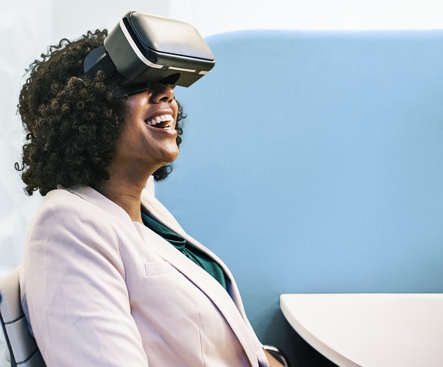 smiling business woman sits at a desk wearing a virtual reality headset