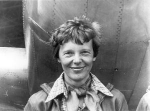 Amelia Earhart standing under nose of her Lockheed Model 10-E Electra