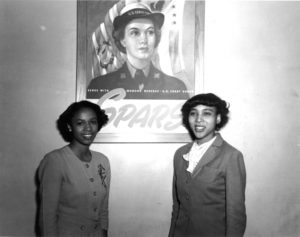 Two African American SPARS recruits in front of a SPARS poster.