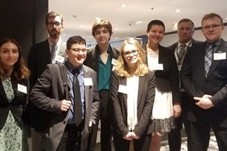 MUN 2018 team, eight people dressed in business wear and name tags pose for a photo as a group