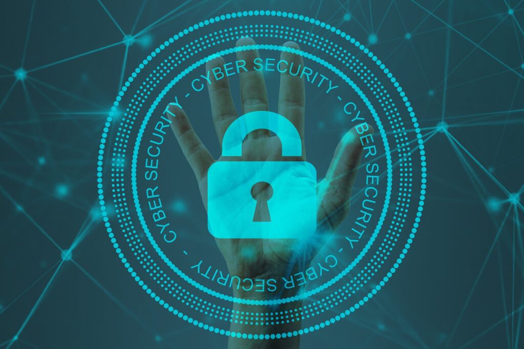 A picture of a circle with the words around it of cybersecurity, a lock in the middle, with a hand in the back.