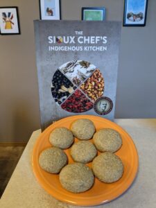 The Sioux Chef's Indigenous Kitchen cookbook and sunflower cookies on a plate