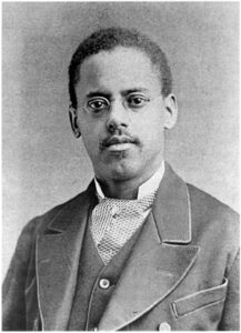 Black and white portrait of Lewis Latimer wearing a suit and looking at the camera