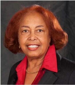 Color portrait of Patricia Bath, a smiling woman with bobbed red hair, a red shirt, and black blazer