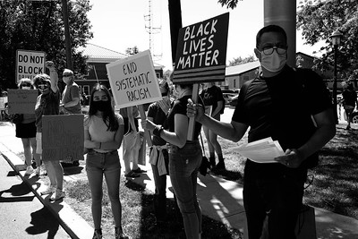 Black and white photo of Black and white protesters holding signs like "End Systemic Racism" and "Black Lives Matter"