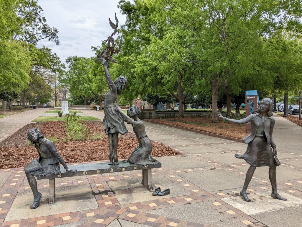 "Four Spirits" sculpture of three girls on a bench with doves and another girl standing
