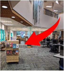 Popular Reading cart in library with red arrow pointing to location in back left
