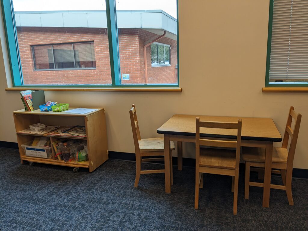 Child-size table and chairs and shelf with coloring books, activity kits, and children's books