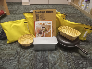 Yellow bags surround a display of a gingerbread house kit, bread pans, and a cast iron